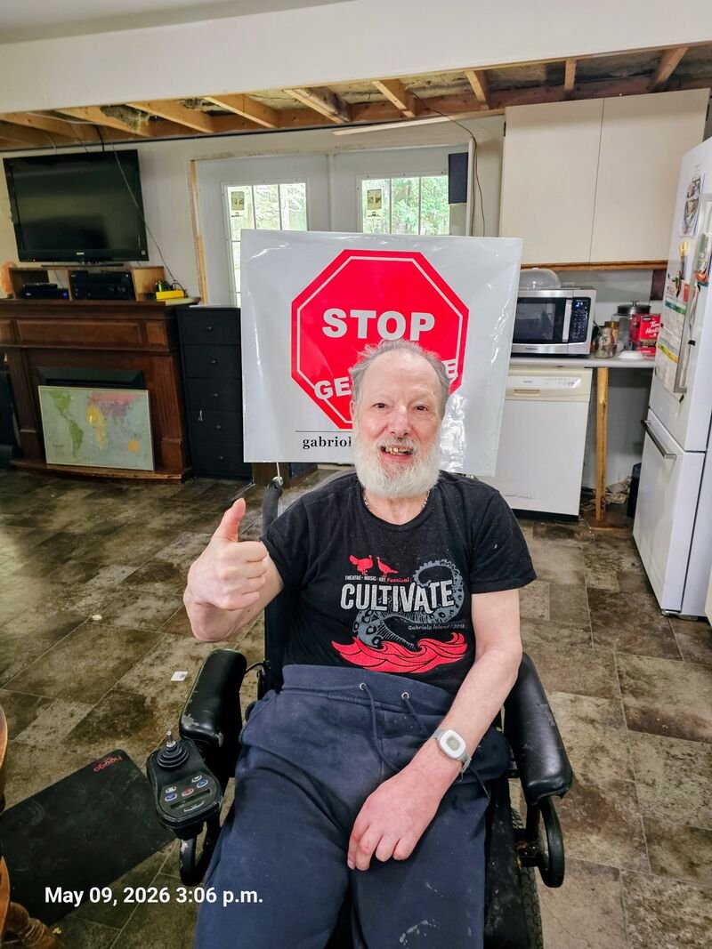Guest with his new Stop Genocide polybag sign on North Road, Gabriola