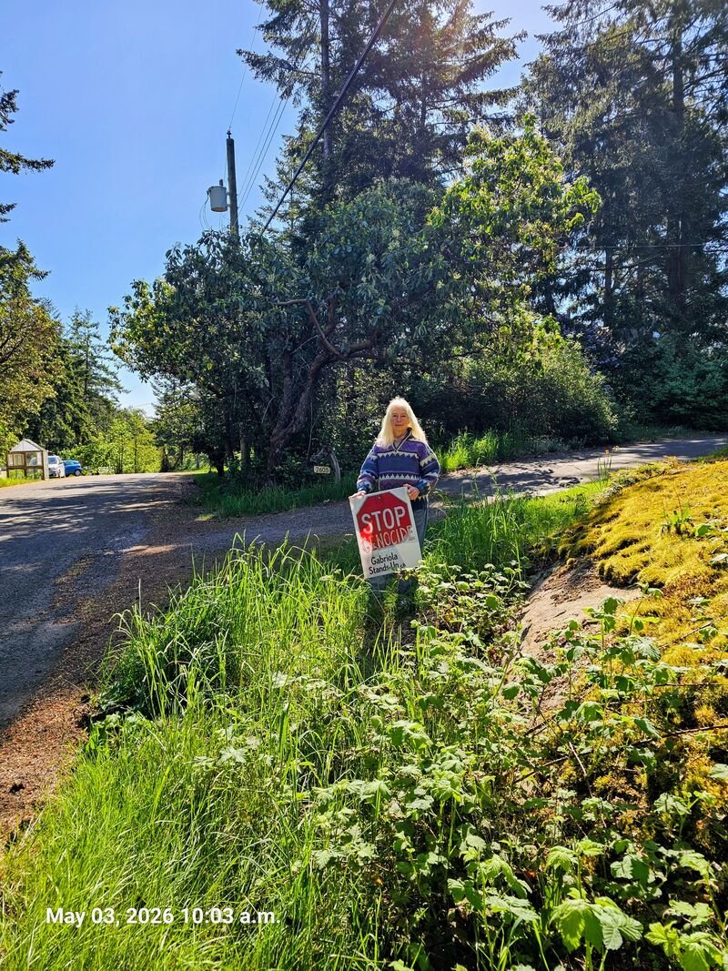Heather with her Stop Genocide sign on Islands View Drive, Gabriola