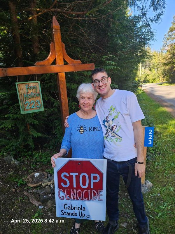 Shri and Alexander with their Stop Genocide sign on Malaspina Drive, Gabriola
