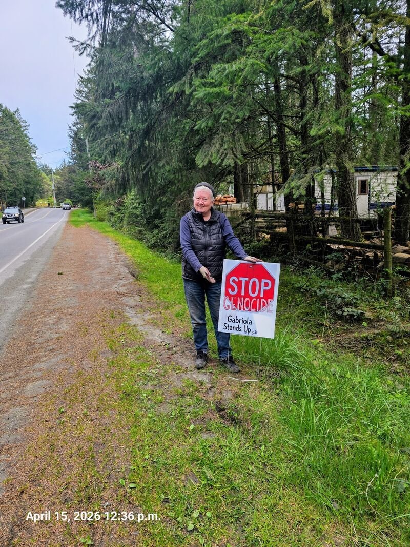 Taylor Turrie with her Stop Genocide sign at Paradise Island Alpaca Farm, Gabriola