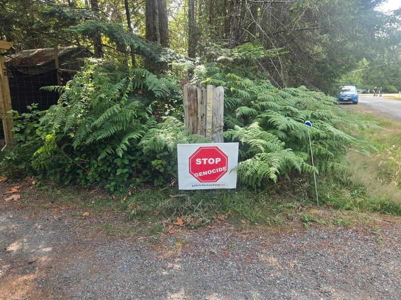 Trisha and Kent's Stop Genocide sign on Sea Lovers, Gabriola